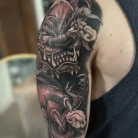 Black and grey dragon and skull half sleeve on an upper arm — by Adam Crane