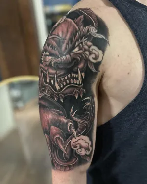 Black and grey dragon and skull half sleeve on an upper arm — by Adam Crane