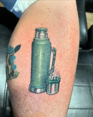 Colour vintage thermos flask and paint tins tattooed on an upper arm — by Adam Crane