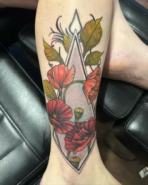 Neo-traditional poppies and foliage inside a geometric diamond on an arm — by Adam Crane