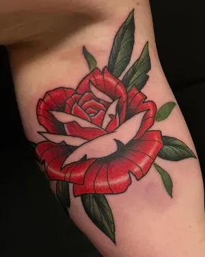 Neo-traditional red rose with green leaves on an upper arm — by Adam Crane