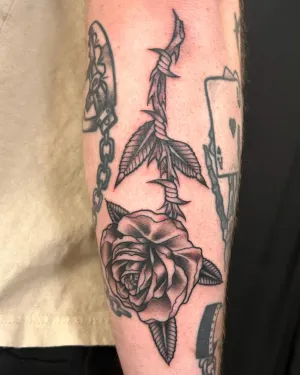 American traditional dagger through a rose on a forearm — by Chay Menke