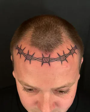 Barbed wire tattooed across a shaved scalp hairline — by Chay Menke