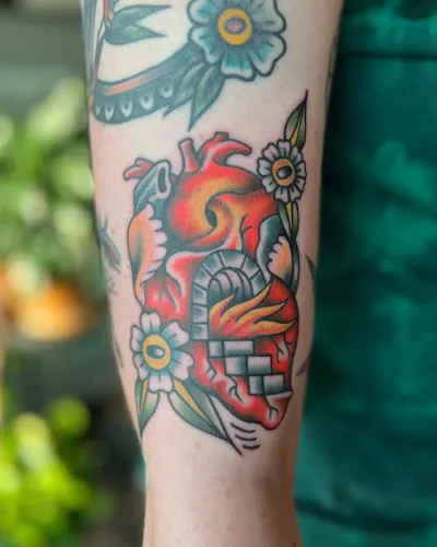 American traditional anatomical heart with flowers on an upper arm — by Chay Menke at Ministry Ink