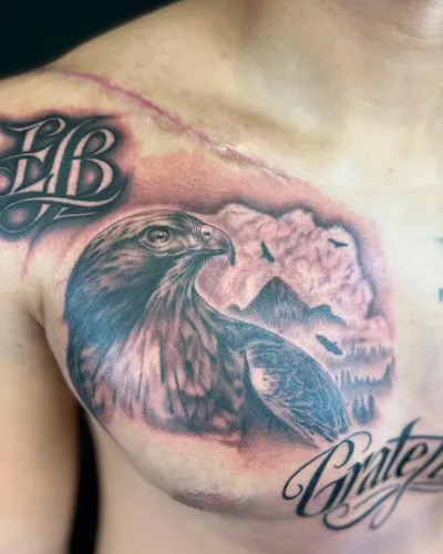 Black and grey eagle and mountain chest piece with Grateful script — by Chay Menke at Ministry Ink