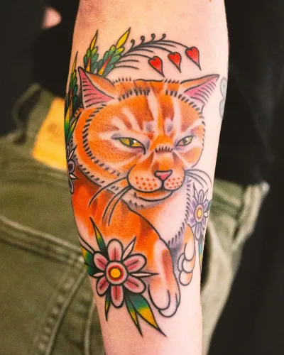 Colour American traditional ginger cat with flowers on a thigh — by Chay Menke at Ministry Ink