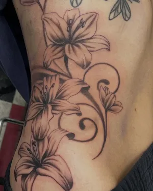 Fine line lilies and trailing vines across the ribs — by Gabriel Gonzalez
