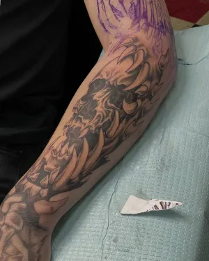 Black and grey leg sleeve in progress with stencil still visible — by Gabriel Gonzalez