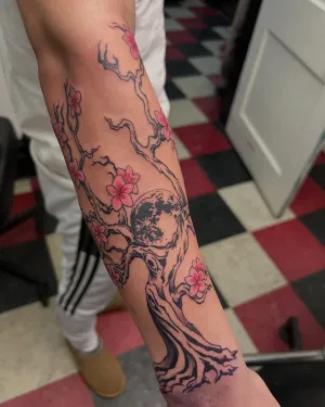 Fine line cherry blossom branch running down a forearm — by Gabriel Gonzalez
